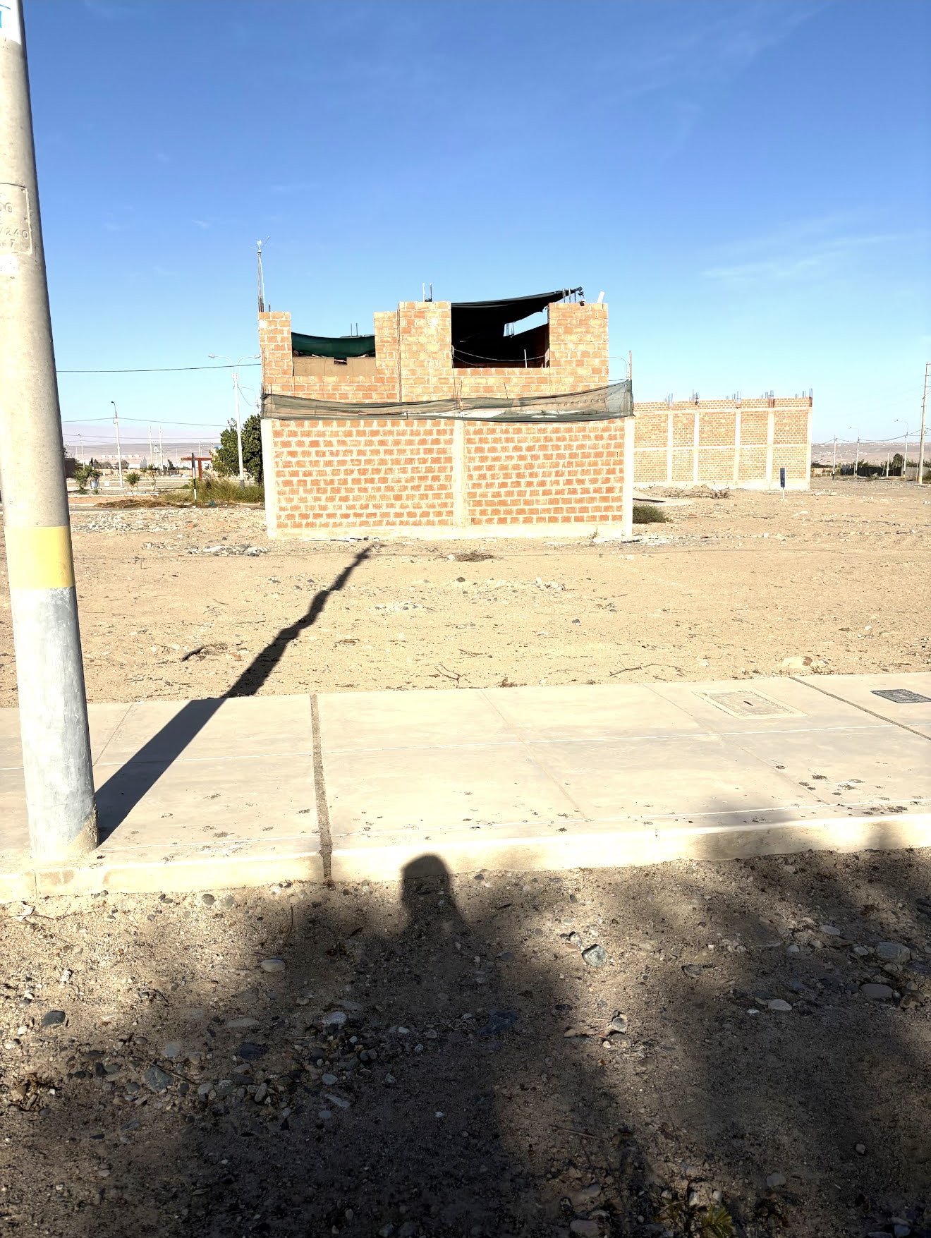 Foto real del terreno 96m2 en La Planicie de Tacna frente a avenida con vereda y poste de luz